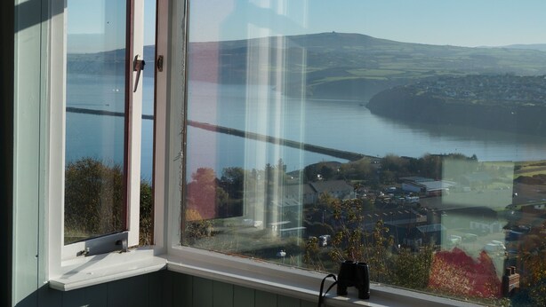 A window with a view of a body of water, a bridge, and a town. - Brynsior, Chalet on the hill in Goodwick with stunning sea views (Fishguard)