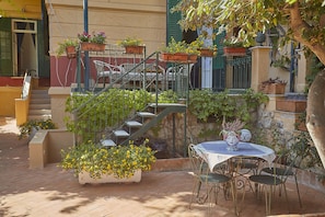 A courtyard with a staircase, outdoor seating, and potted plants.