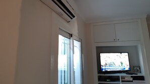 Ein Zimmer mit einer Schiebetür, einer an der Wand montierten Klimaanlage, einem Fernseher auf einem Schrank und einem Schrank darüber.