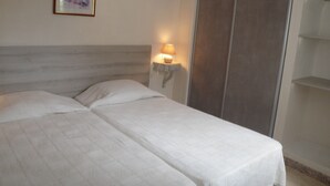 Ein Schlafzimmer mit einem Bett, einem Nachttisch mit Lampe, einem gerahmten Bild an der Wand und einem Schiebetürenschrank.