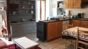 Una cocina compacta con armarios de madera, microondas integrado y un pequeño comedor con mesa y sillas.
