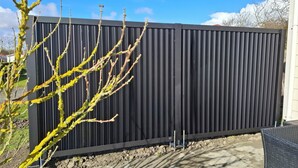 A modern building with a dark vertical panel facade, a paved ground, and a tree with yellow flowers in the foreground. - Chalet Zonnebloem for 6 people, lots of privacy in a quiet park (Serooskerke (W))