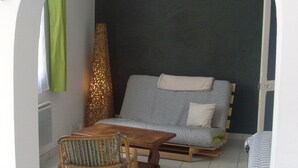 Une pièce chaleureuse avec un canapé, une table en bois et un fauteuil en osier.