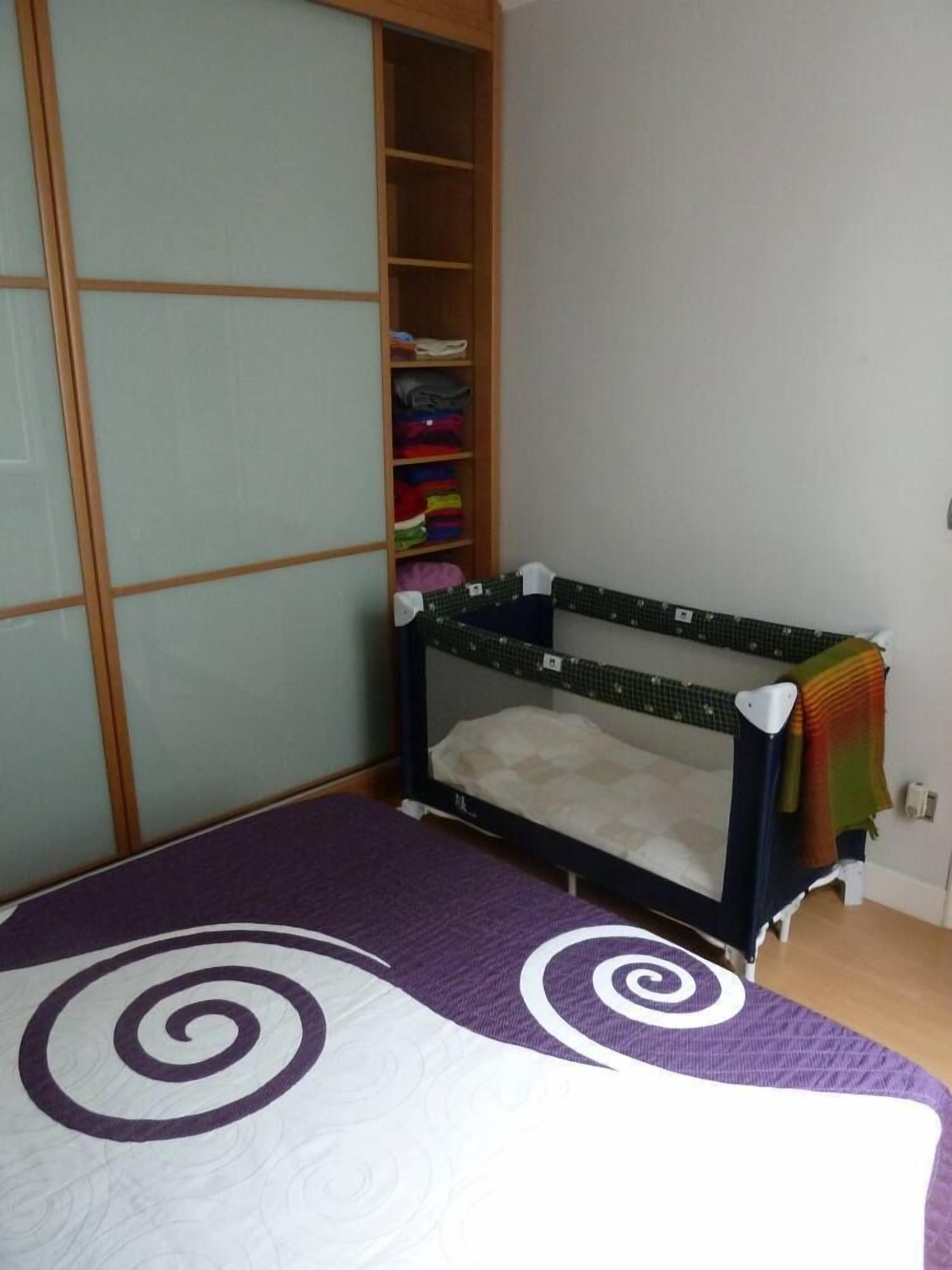 Una habitación con literas, un armario con puertas correderas y una estantería con ropa doblada.