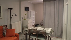 A compact living space with a dining table, chairs, a sofa, a radiator, a television, and a sliding door. - Apartment near Gros beach, ESS00033 (San Sebastián)