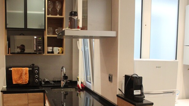 A modern kitchen with wooden cabinets, a black countertop, and a built-in oven. - Apartment near Gros beach, ESS00033 (San Sebastián)