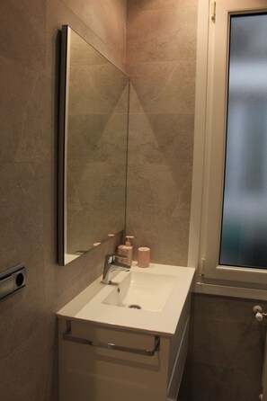 Un bany modern amb un mirall gran, un lavabo i una finestra.