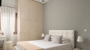 Een slaapkamer met een groot bed, een kledingkast, een nachtkastje en een bedtafeltje.