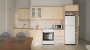 Een compacte keuken met houten kastjes, een magnetron, een fornuis en een koelkast.