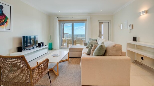 A modern living room with a sofa, a TV, a coffee table, and a wicker chair. - Bay H Modern townhouse very central, fabulous sea views! (Carvoeiro)