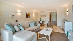A modern living room with a sofa, coffee table, and dining area. - Bay H Modern townhouse very central, fabulous sea views! (Carvoeiro)