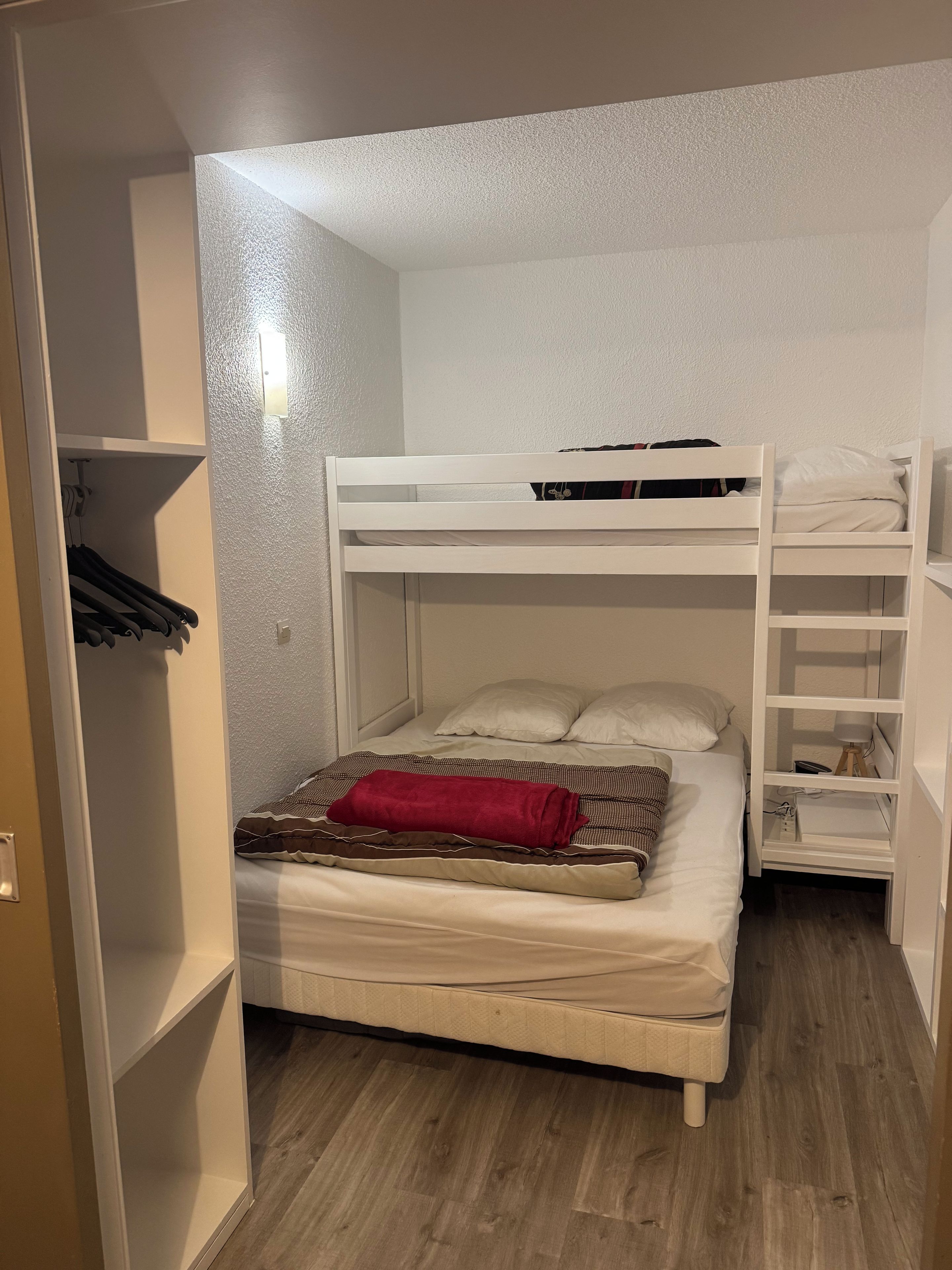 A bunk bed room with a wardrobe and a desk.