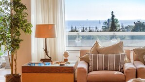 A living room with a sofa, a lamp, a foosball table, and a view of the sea.