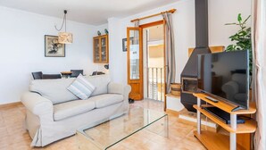 Un salon comprenant un canapé, une table basse en verre, un téléviseur, une cheminée et une porte donnant sur un balcon.