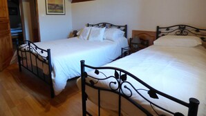 A bedroom with two beds, wooden ceiling beams, and a painting on the wall. - Stunning Valley Views from our 3* Gîte bordering the Cévennes and Grands Causses (Nant)