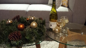 Ein Glastisch mit einer Weinflasche, Gläsern und einer Weihnachtsdekoration.