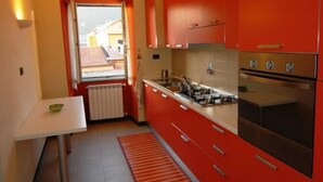 A compact kitchen with red cabinets, a white countertop, and a window with a view. - CENTRALLY quiet and typical residence -150 mt. from the sea (Levanto)