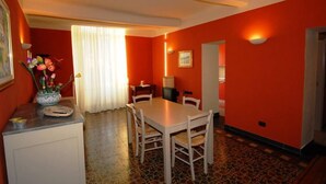 A dining area with a white table and chairs, a vase of flowers on a counter, and a window with curtains. - CENTRALLY quiet and typical residence -150 mt. from the sea (Levanto)