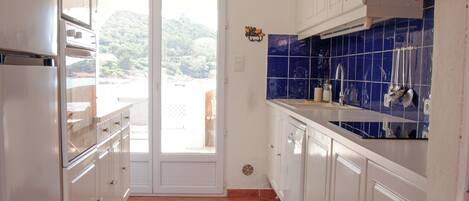 A kitchen with white cabinets, a tiled backsplash, and a view through the door.
