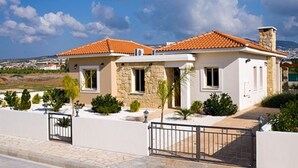 Une maison à deux étages avec une façade en pierre, un toit en tuiles et une entrée fermée par un portail.