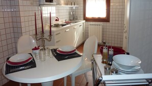 A compact kitchen with white cabinets, a microwave, and a window with a wooden frame. - Charming home behind Piazza San Marco, panoramic view over the rooftops of Venice (Venezia)