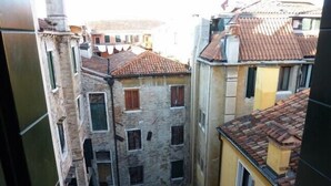 A narrow alleyway between buildings with stone facades and red-tiled roofs. - Charming home behind Piazza San Marco, panoramic view over the rooftops of Venice (Venezia)
