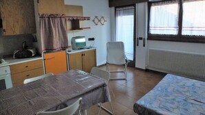 A compact room with a kitchenette, a dining area, and a bed.
