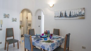 Ein Essbereich mit einem Tisch für vier Personen, ausgestattet mit gestreiften Stühlen und einer Tischdecke mit blauem Muster.