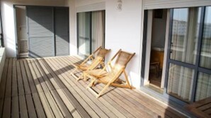 A wooden deck with three wooden lounge chairs, a sliding glass door, and a window with curtains. - Apartment/ flat - Lagos (Lagos)