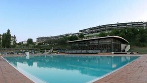 A rectangular swimming pool with a brick border, surrounded by a building with a curved roof and a balcony overlooking the pool. - Apartment/ flat - Lagos (Lagos)
