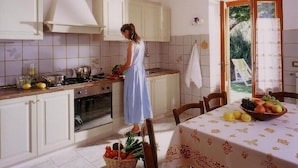 Uma cozinha com armários brancos, um fogão e uma mesa com uma fruteira.