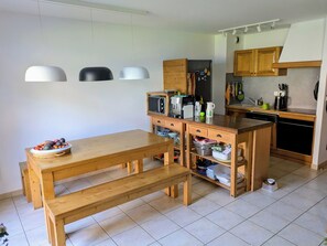 Eine moderne Küche mit Holzschränken, einer zentralen Kochinsel und einem Esstisch mit Bänken.