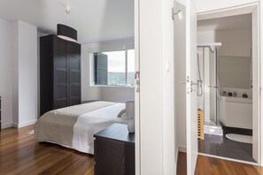 Un dormitorio con cama, armario y baño con ducha e inodoro.