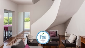 A modern living room with a curved ceiling, a dining area with a pink tablecloth, and a view of greenery outside. - House of the Camellias, modern constriction - Next to the City Gates (Sete Cidades)