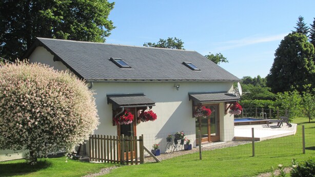 Une maison à deux étages avec un toit en pente, une cour clôturée et une petite piscine.