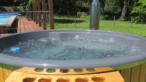 Un bain à remous avec une terrasse en bois et une piscine en arrière-plan.