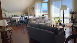 A spacious living area with a dining table, blue chairs, a sofa, and a lamp.