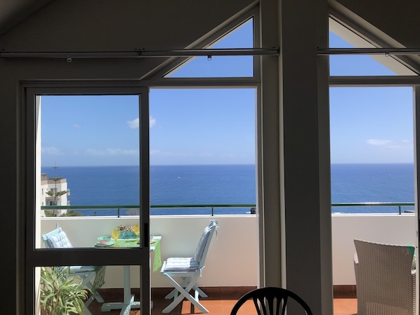 A balcony with a view of the ocean, a table with chairs, and a potted plant. - Large penthouse 160m2, quiet with sea view, in the tourist area Funchal (Funchal)