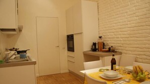 A compact kitchen with white cabinets, a built-in oven, and a dining area with a yellow tablecloth. - Rome: NEW from 3 up to 11 people Central, Modern and bright (Roma)