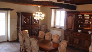 Comedor con mesa y sillas de madera, una araña y un aparador con vajilla.