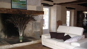 Una sala de estar con un sofá blanco, una chimenea con un jarrón decorativo y un cuadro en la pared.