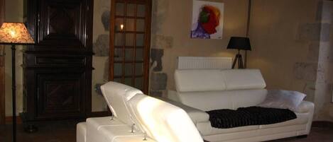 Un salon chaleureux avec un canapé blanc, un banc, une cheminée et un tableau accroché au mur.