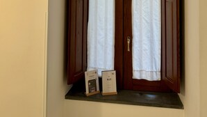 A room with a wooden door and a small window with sheer curtains. There are two informational cards on the window sill.