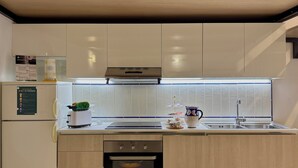 A modern kitchen with a built-in oven, a stainless steel sink, and a window above the countertop.