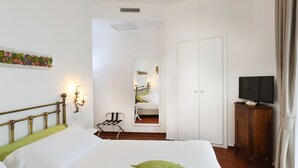 A bedroom with a bed, a chair, a TV stand, and a door.