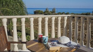 A wooden table with chairs on a balcony overlooking the sea. - Villa Astro -  a beach villa with heated pool that sleeps 8 guests  in 4 bedrooms (Paphos)