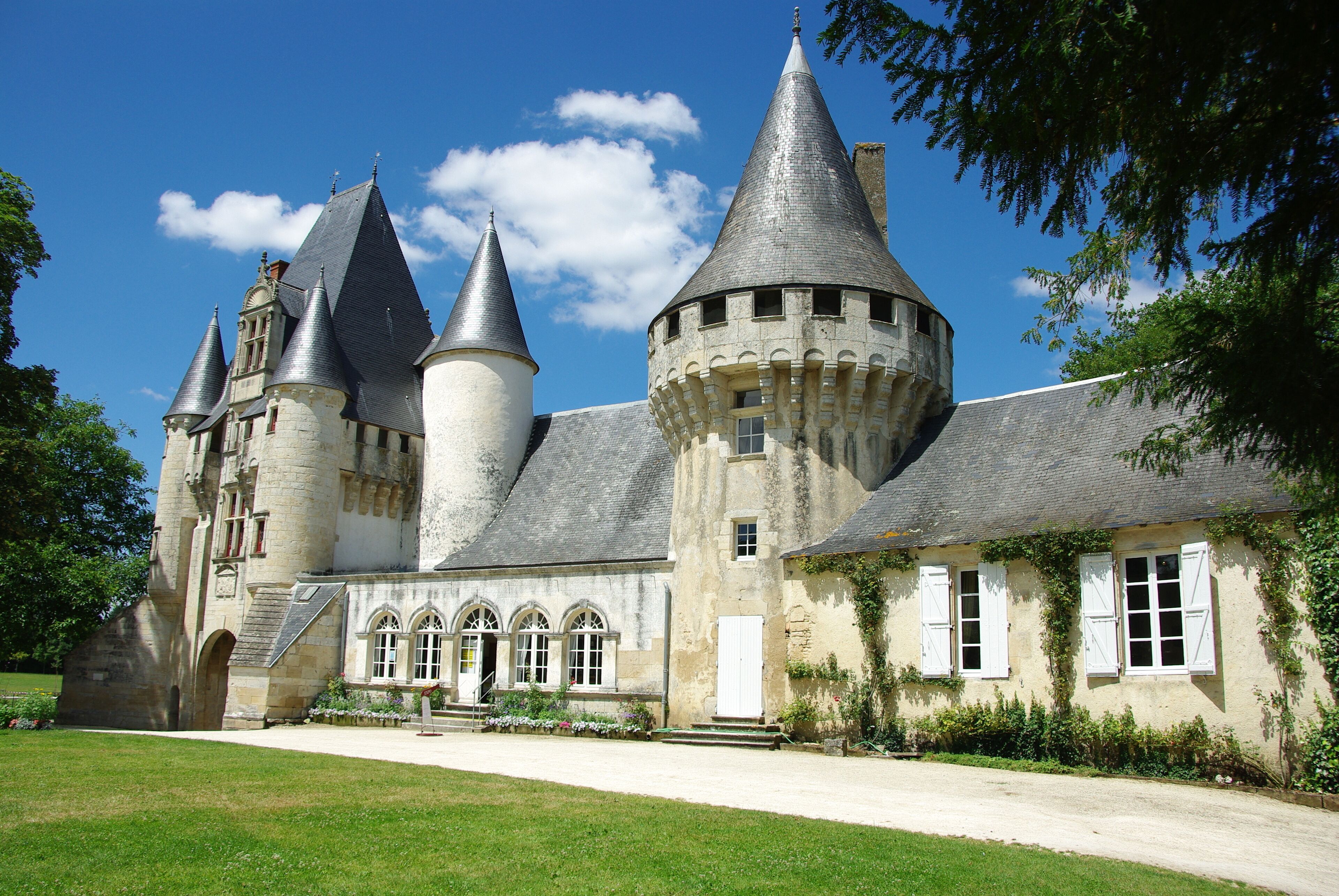 A historic castle with multiple towers, a courtyard, and a well-maintained garden.