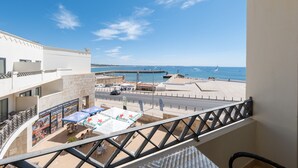Un balcone con vista su una spiaggia e un molo. Sono presenti aree salotto all'aperto con ombrelloni e un cartello Heineken.