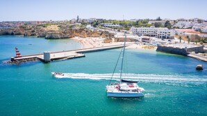 Una cittadina costiera con un porto turistico, barche e un faro.