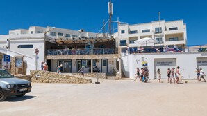 Un edificio fronte spiaggia con facciata in pietra, numerosi balconi e cielo azzurro.